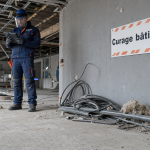 Curage batiment en cours : sol béton, poussière et technicien en EPI