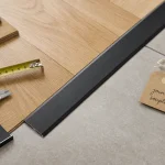 Jonction nette salon parquet cuisine carrelage : seuil aluminium noir mat entre chêne et carrelage grès
