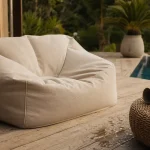 Pouffe exterieur XL beige sur terrasse bois, vue côté, gouttelettes