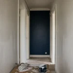 Couleur peinture pour couloir : mur bleu nuit et blanc cassé, rouleau et pot de peinture
